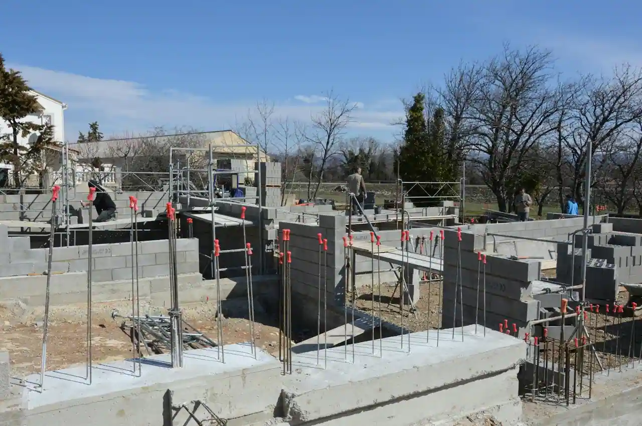 Chantier de construction d'un garage en parpaing avec dalle béton fraîchement coulée et murs en cours de montage