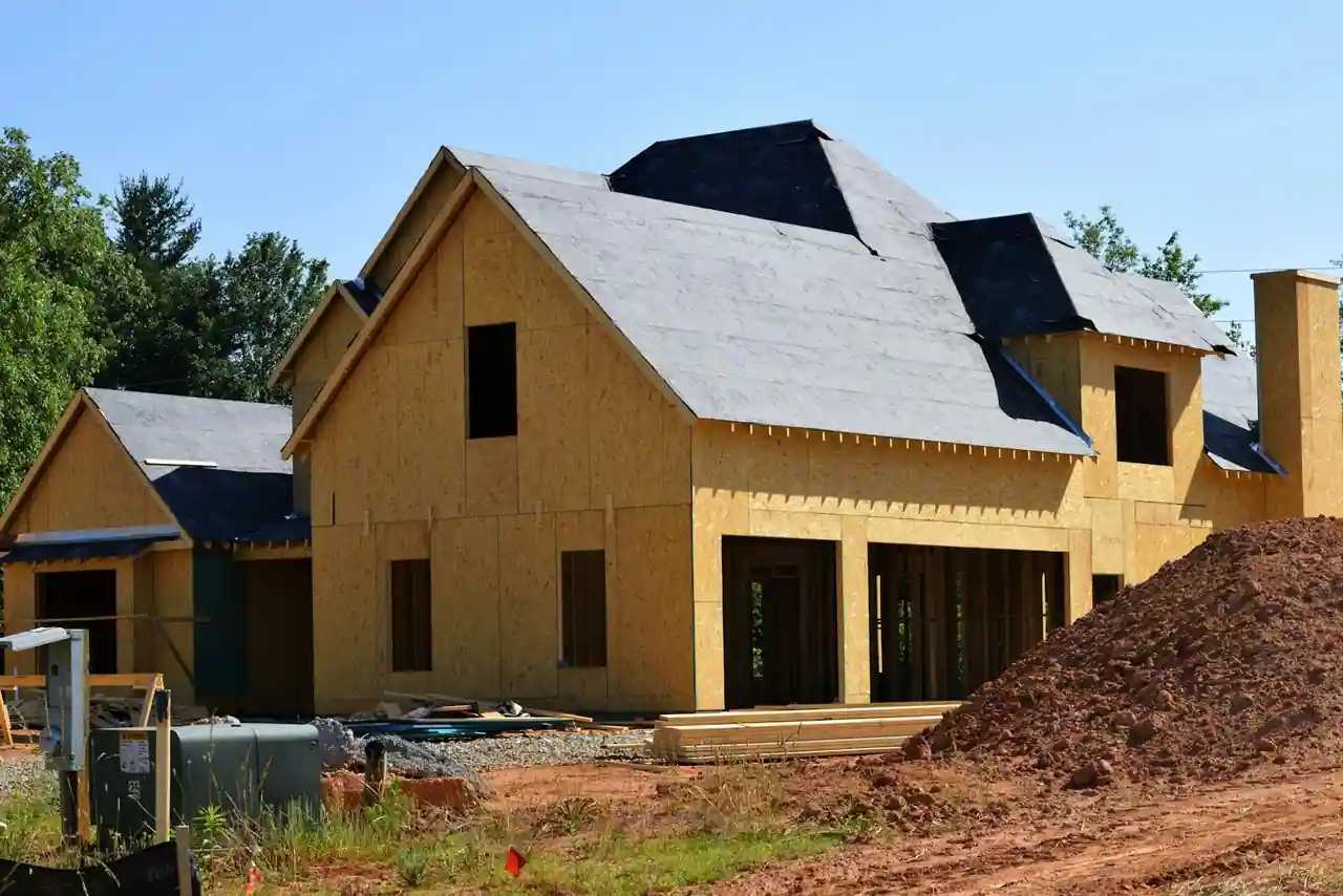 Chantier de construction maison individuelle avec murs en parpaing et charpente bois en cours de pose