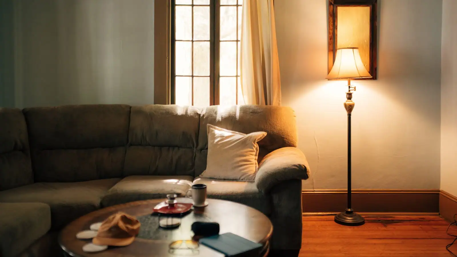 Séjour lumineux avec canapé clair, tapis en laine et lampe d'angle, vue sur baie vitrée