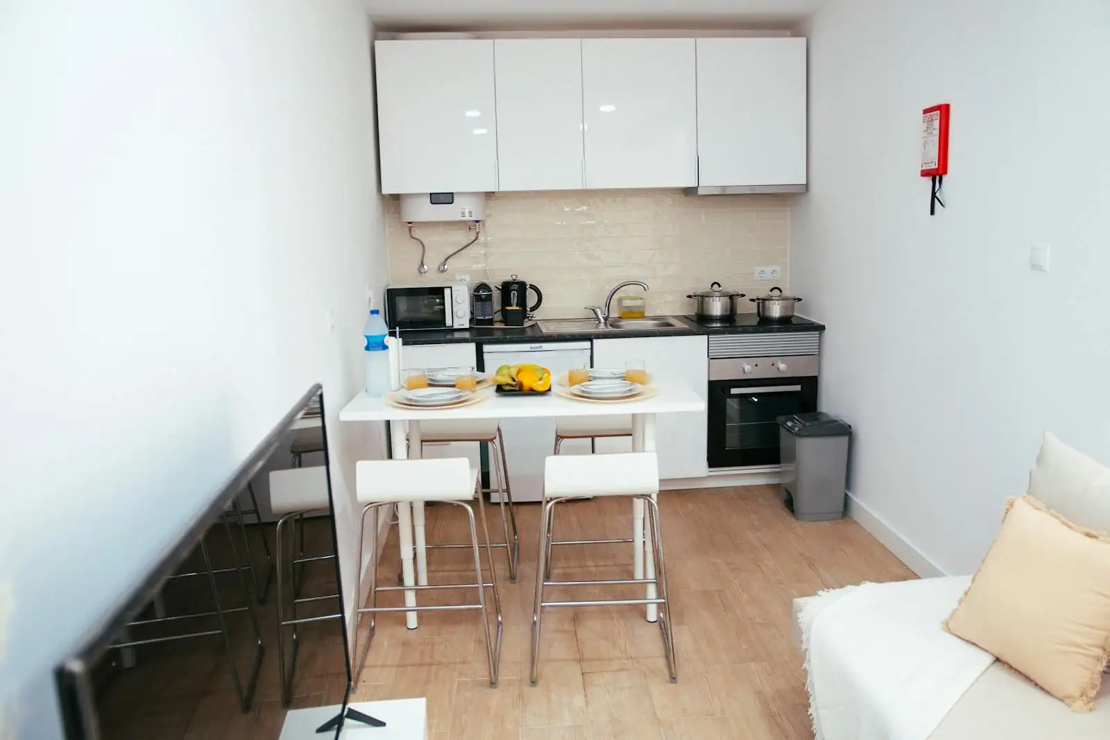 Cuisine ouverte moderne dans un petit appartement avec plan de travail en bois clair et verrière