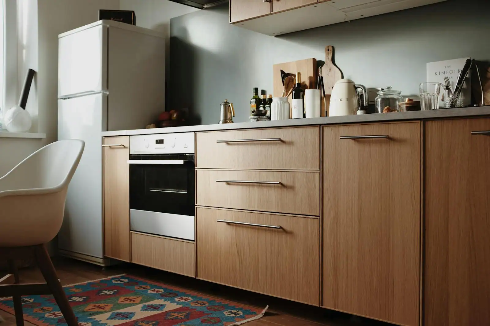 Cuisine moderne avec tiroirs ouverts et casseroliers compartimentés, façades en bois clair, plan de travail dégagé