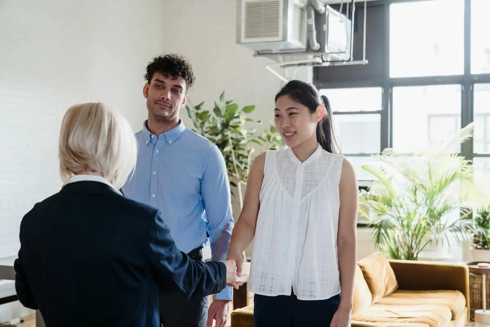 Couple consultant des documents immobiliers avec un agent dans un salon lumineux