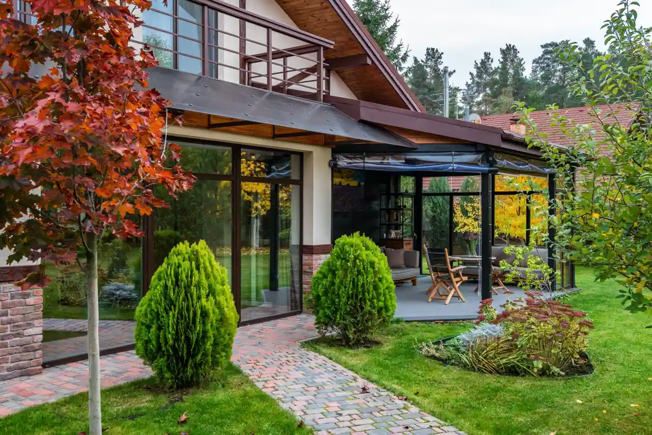 Jardin extérieur aménagé avec une terrasse couverte, une allée pavée et des massifs