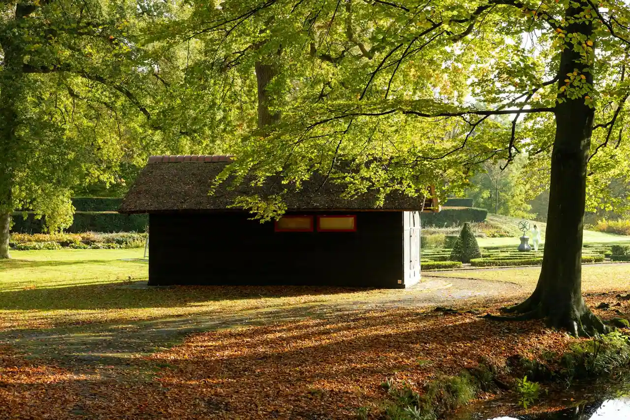 Cabane de jardin en bois à toit en pente, installée dans un parc arboré aux feuilles d automne.