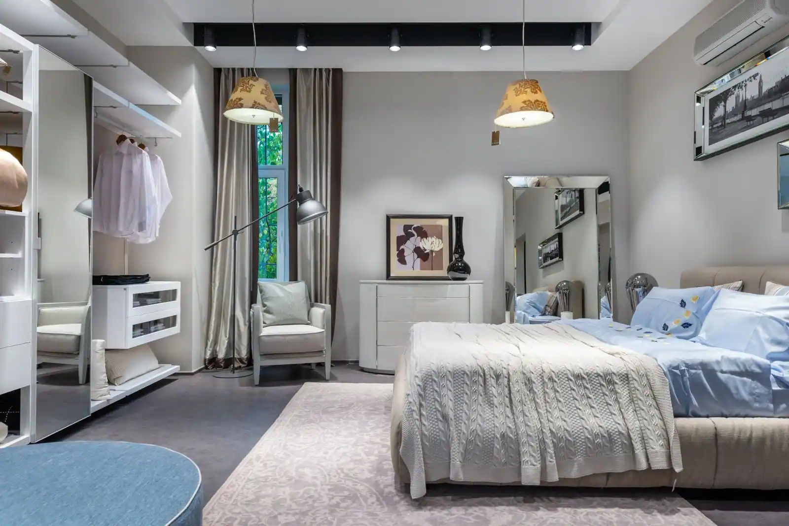 Chambre décorée aux tons doux gris et bleutés, lit habillé d’un plaid en grosse maille, coussins et tapis.