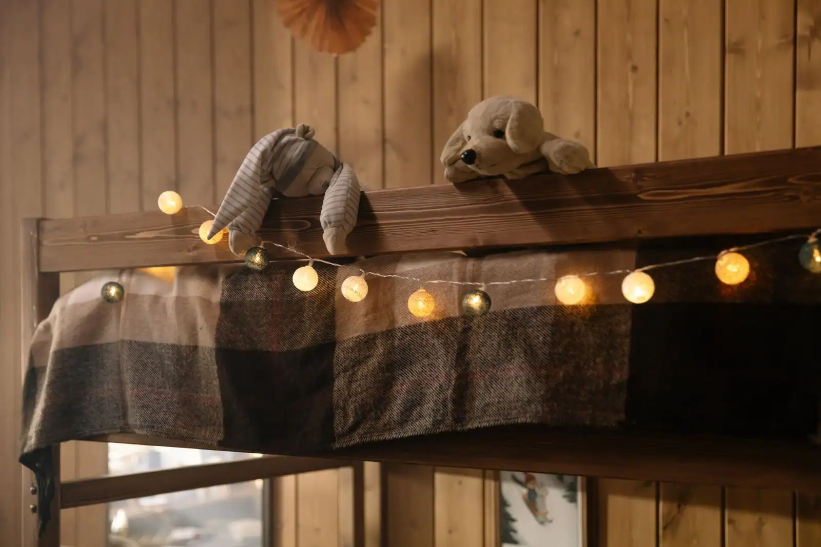 Chambre d'enfant cosy en bois avec guirlande lumineuse chaude et peluches, ambiance douce