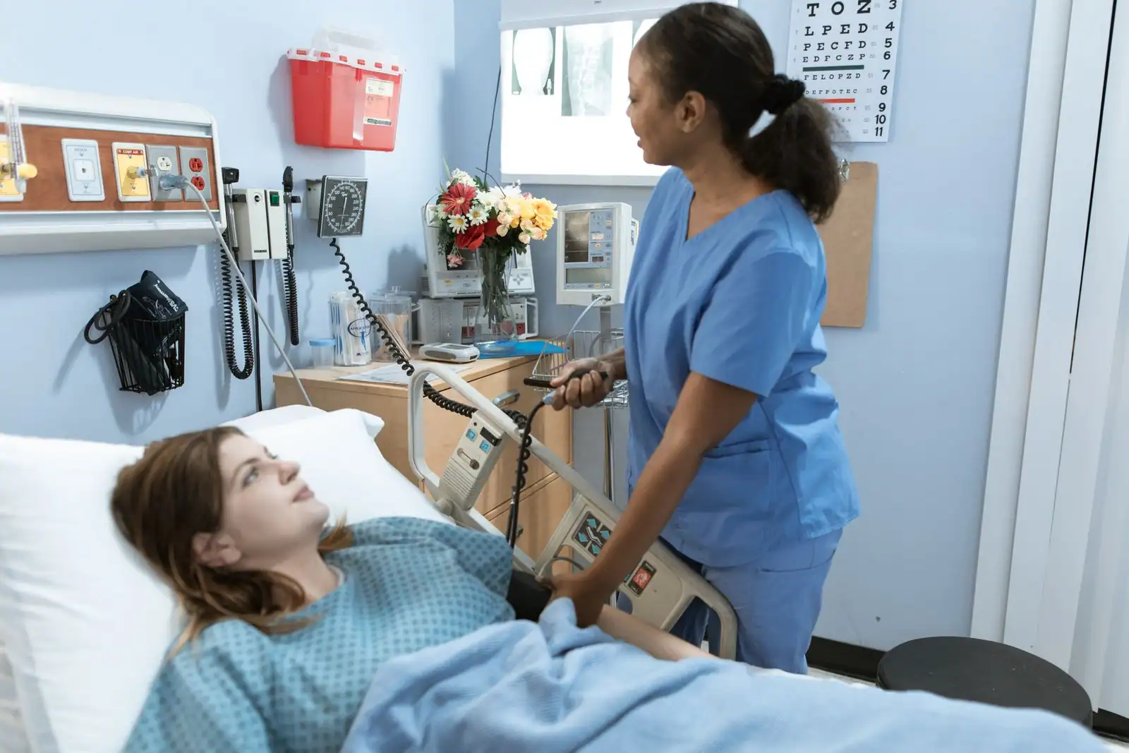 Patiente allongée dans un lit médicalisé à l'hôpital, une soignante à son chevet.