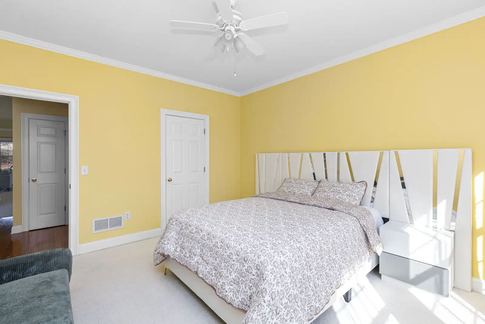 Chambre aux murs peints en jaune pâle, avec un lit double et un sol clair, décoration lumineuse