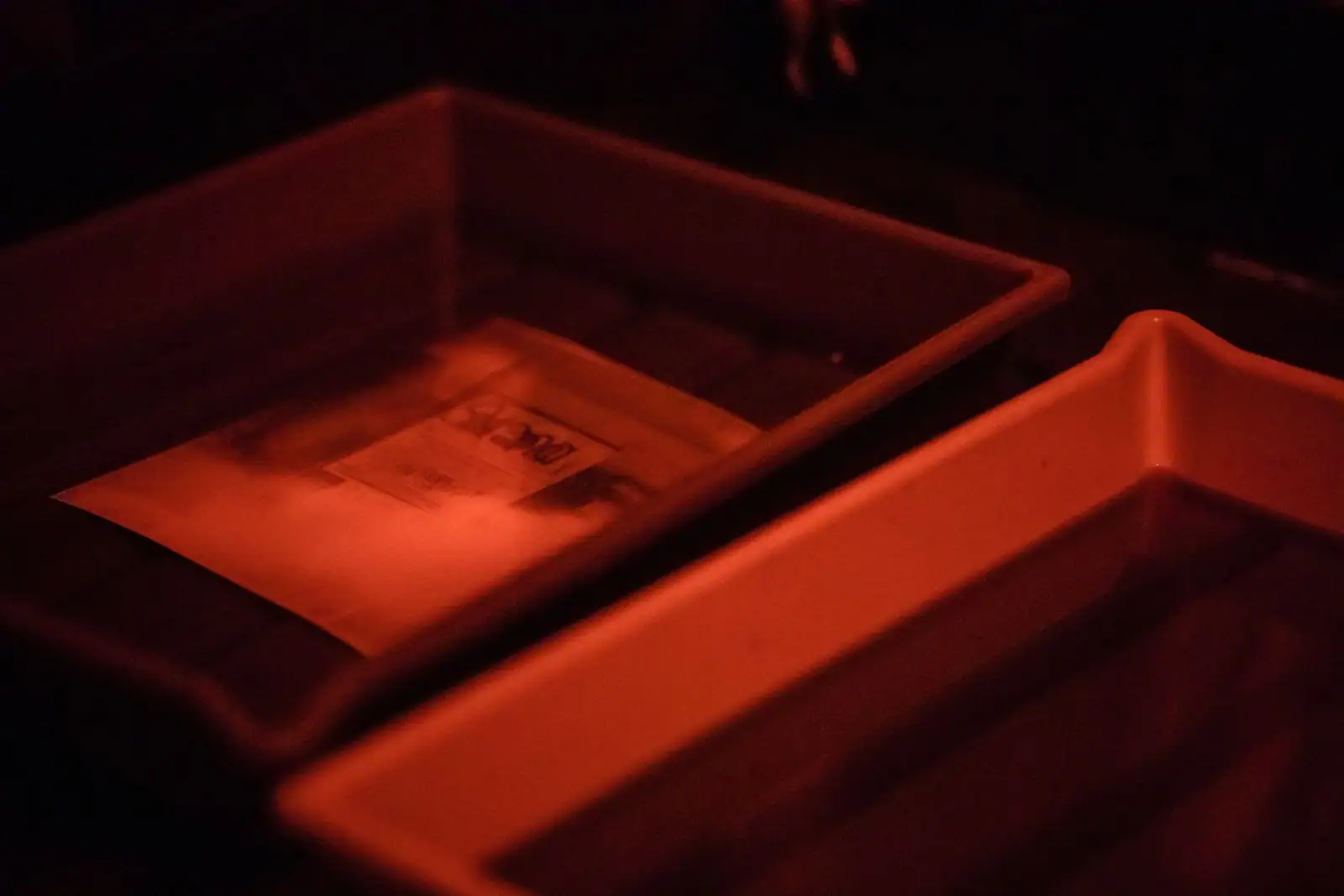 Chambre noire photographique éclairée en lumière rouge inactinique avec cuvettes de développement