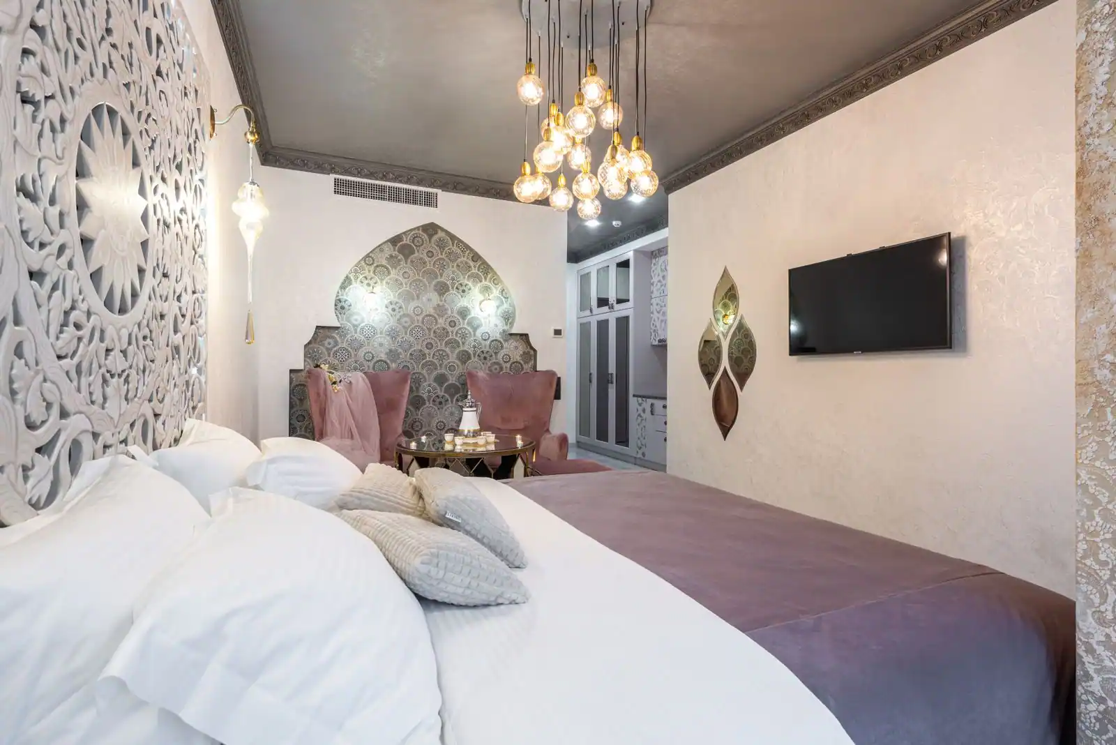 Chambre de style oriental : panneau de bois ajouré, niche en arc et mosaïque, suspensions lumineuses.