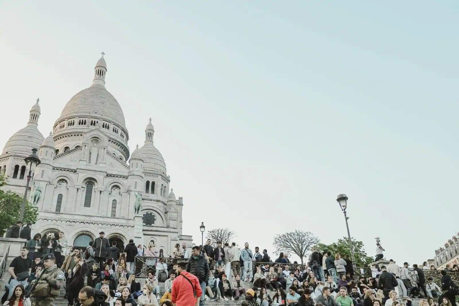 La basilique du Sacré-Cœur de Montmartre et ses coupoles blanches, au-dessus de la foule sur les marches.