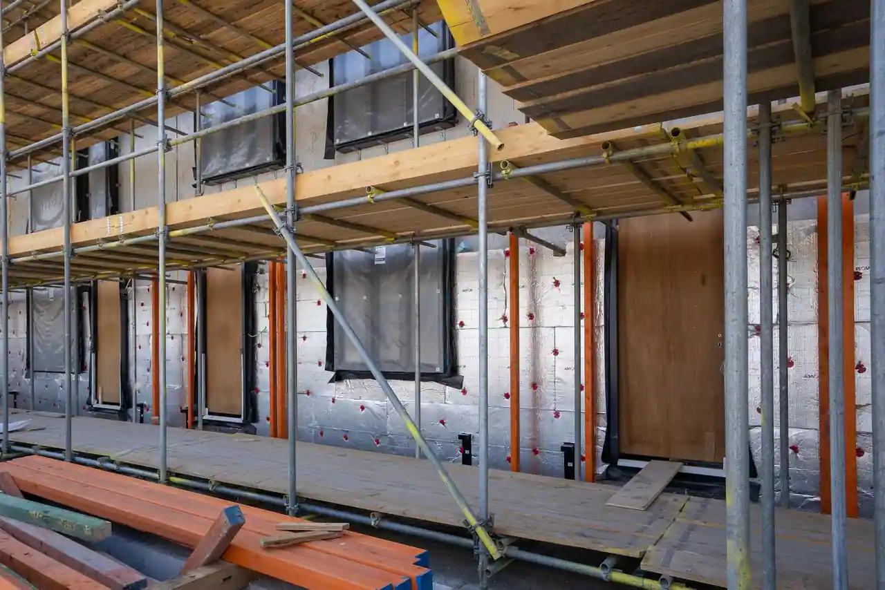 Façade de maison individuelle en construction avec échafaudage et isolation extérieure