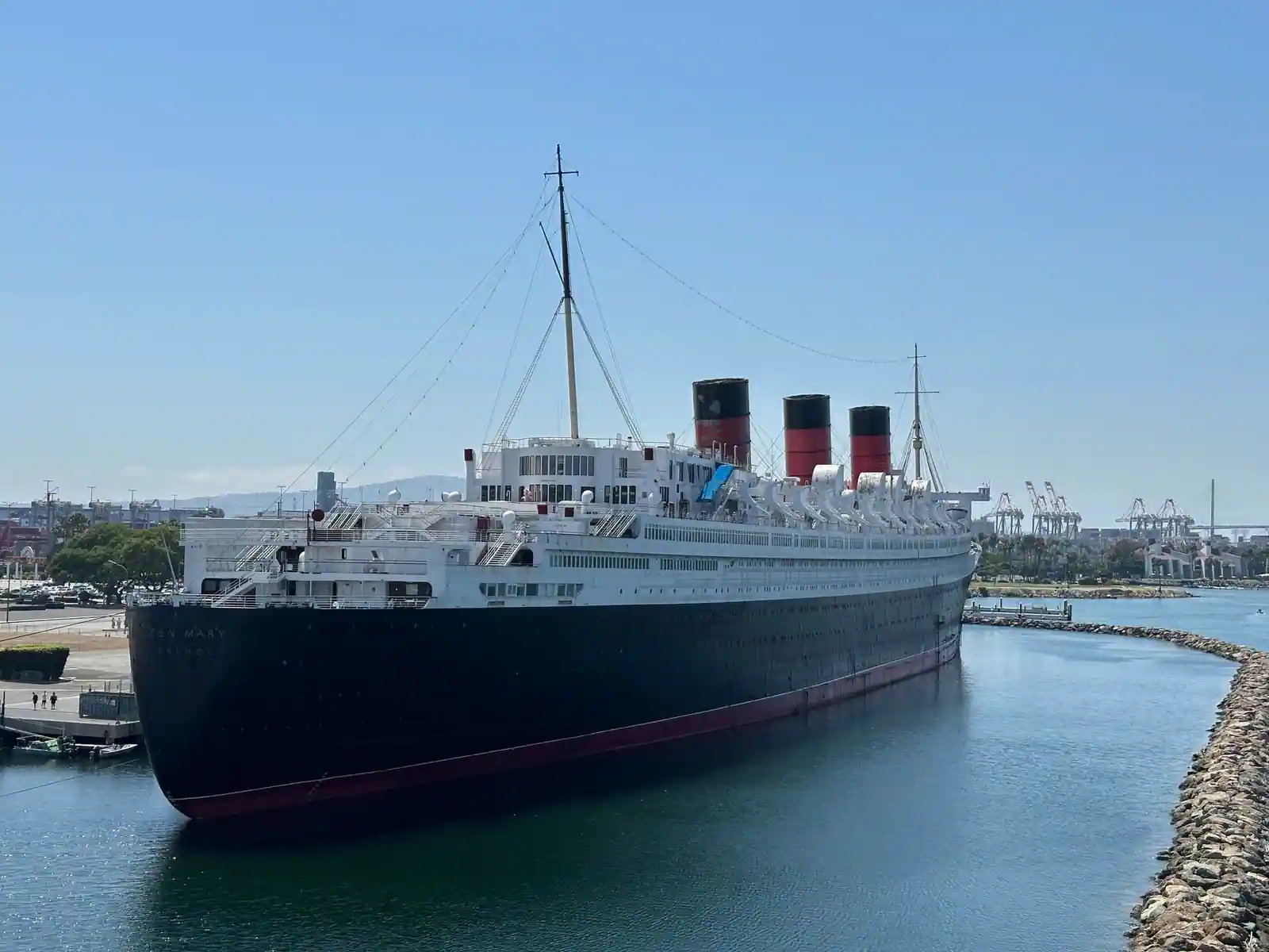 Paquebot transatlantique classique à trois cheminées et coque rivetée, à quai, évoquant l'ère du Titanic.