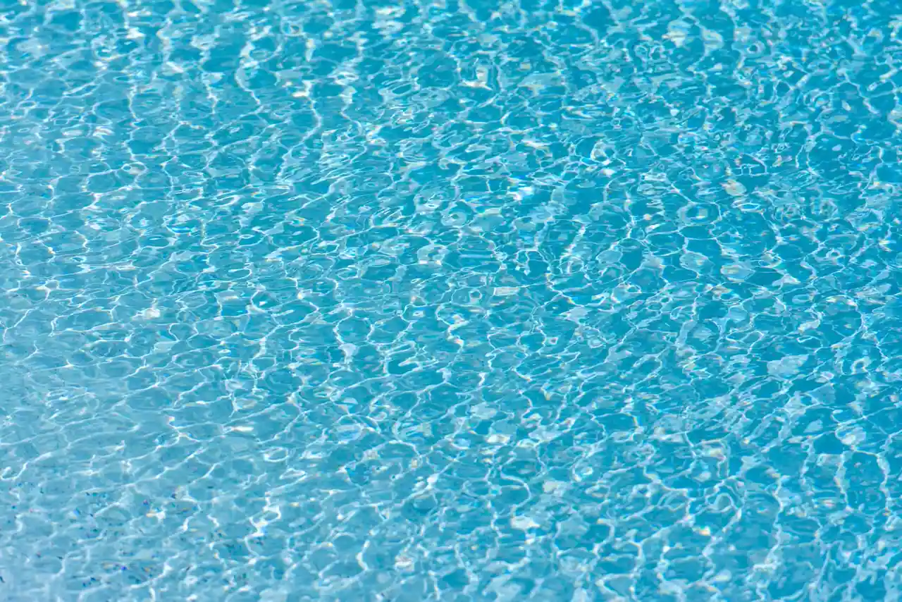Surface ondulée d'une piscine à l'eau turquoise et limpide, évoquant un bassin bien entretenu.