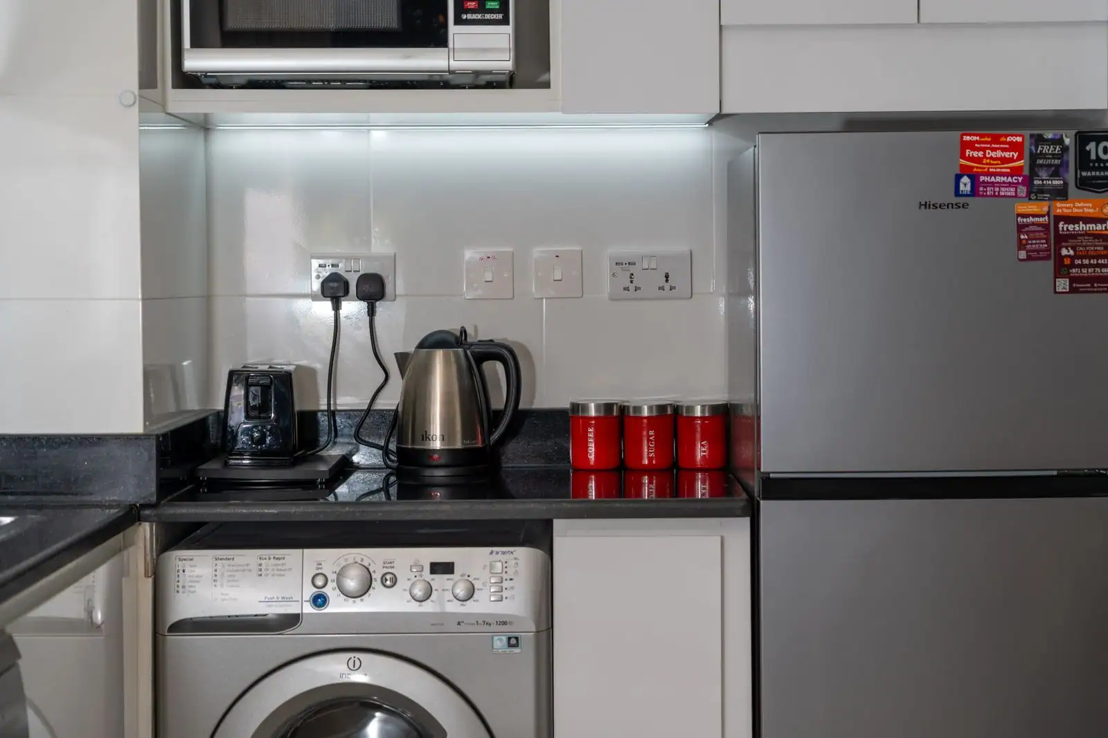 Cuisine domestique équipée d'un réfrigérateur inox, d'un lave-linge et d'un micro-ondes