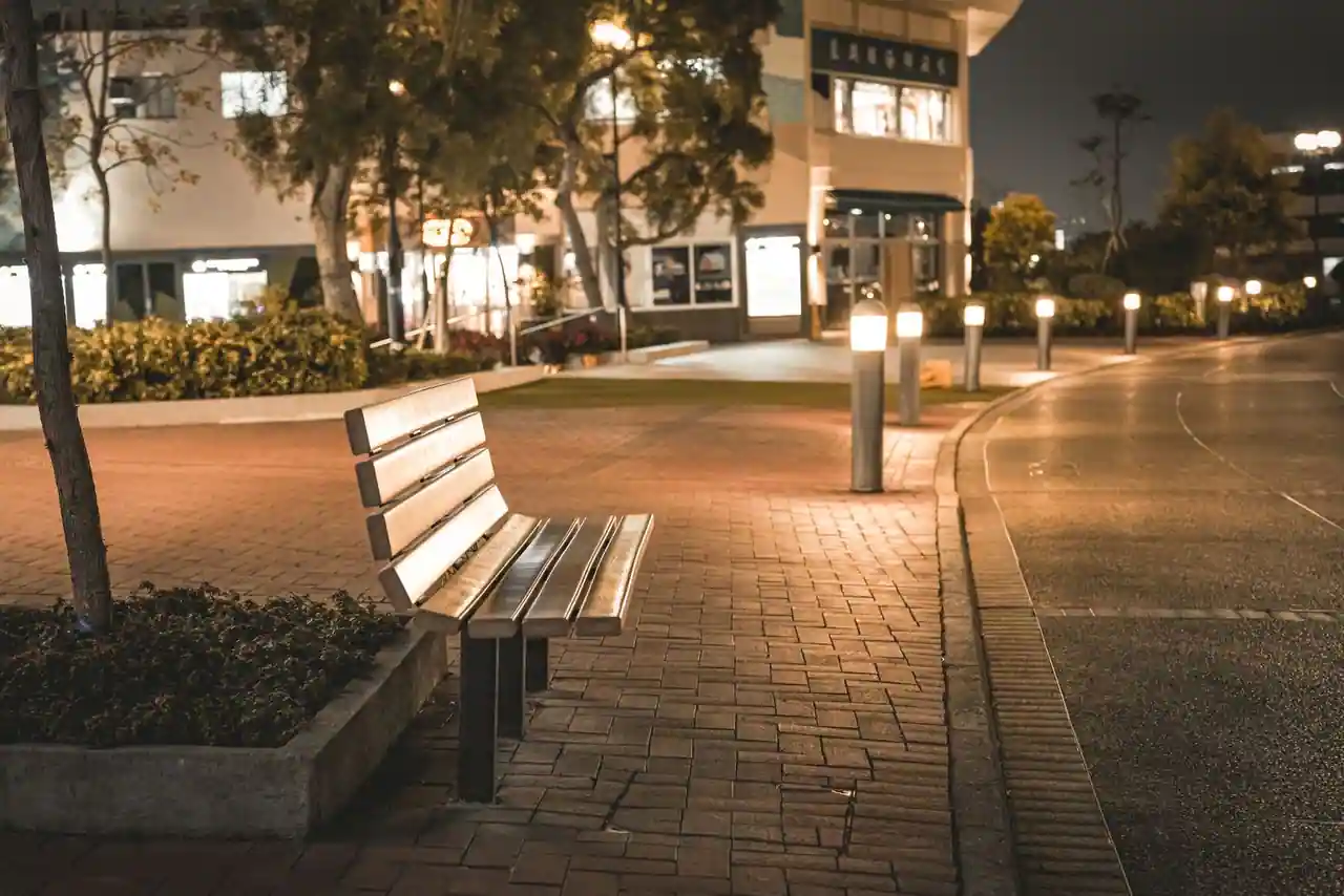 Banc public et lampadaire sur un trottoir de ville, exemples courants de mobilier urbain.