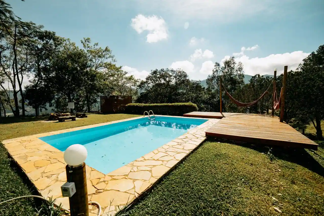 Piscine extérieure à ciel ouvert dans un jardin résidentiel ensoleillé, sous un ciel dégagé.