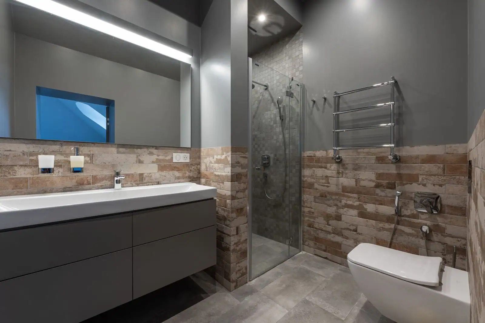 Salle de bain rénovée aux murs carrelés, avec une douche vitrée et un meuble sous vasque.