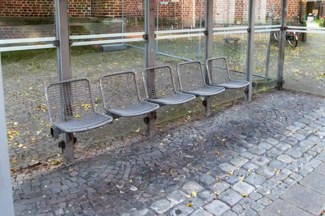 Sièges individuels en métal alignés dans un abribus, un mobilier urbain qui empêche de s'allonger